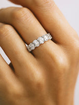 Diamond ring on a person's finger with a neutral background